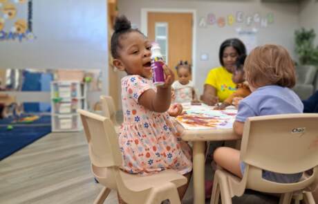 Toddlers enjoying hands-on painting and art time guided by their classroom teacher