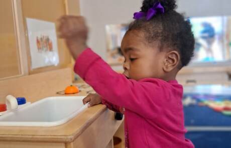 Toddler engaging in dramatic play with our classroom play sink and kitchen set Toddler engaging in dramatic play with our classroom play sink and kitchen set