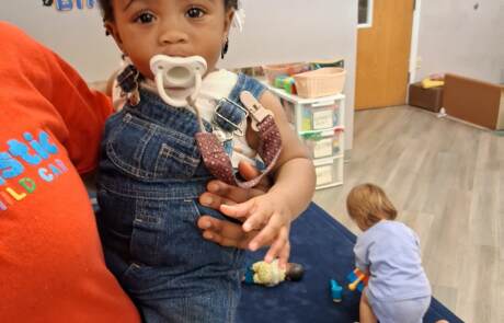 Dedicated teacher holding a toddler securely in a bright Milwaukee daycare classroom
